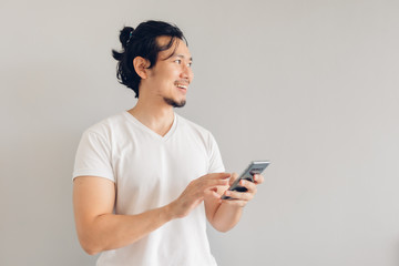 Happy long hair Asian man in white casual t-shirt is using smartphone.