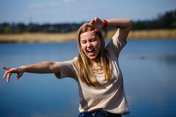 Girl dancing near the lake, sunny weather. A young woman rejoices in life, dances and sings. She has a good mood and a smile on her face.