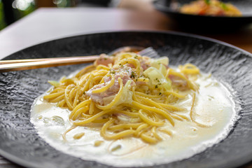 Creamy Spaghetti Carbonara in black dish served in the restaurant.