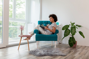 Obraz premium Woman reading a magazine and drinking tea