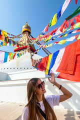 Woman standing under the colourful prayer flags with 'om mani padme hum' mantra written on them...