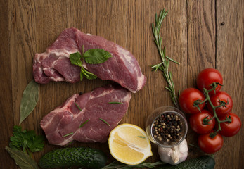Raw juicy meat steaks ready for roasting on a wooden background