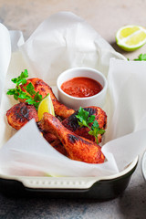 Baked chicken legs in tomato sauce or barbecue sauce in black oven dish.