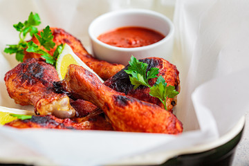 Baked chicken legs in tomato sauce or barbecue sauce in black oven dish.