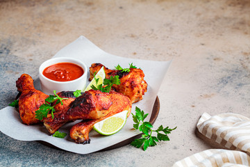 Baked chicken legs in tomato sauce or barbecue sauce on wooden plate, copy space.