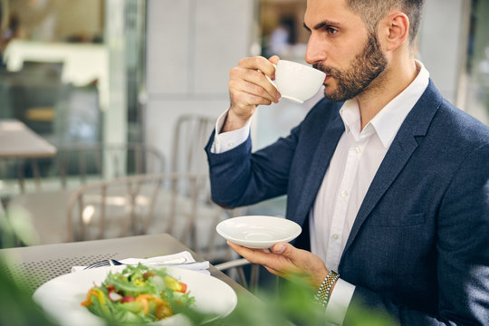 Concentrated bearded male person enjoying aroma coffee - Powered by Adobe