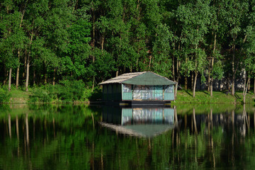 Wooden house on the river with reflection in it,  surrounding by trees