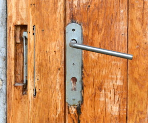 An old retro handle on a wooden door. Antique door handle.
