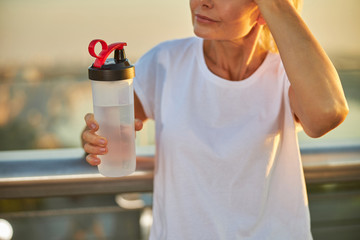 Middle-aged woman in shirt holding bottle of water