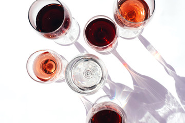 Glasses with red, white and rose wine on a white background.