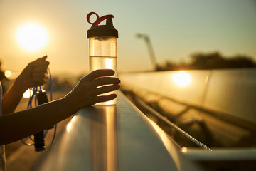 Female hands holding bottle of water and skipping rope