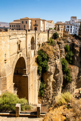 Portrait view of Ronda and its spectacular deep gorge, with a massive stone bridge and arches, built in large rock formations, Ronda, Spain.