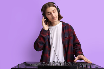 modern club DJ playing mixing music on vinyl turntable, isolated in studio. caucsaian male perform...