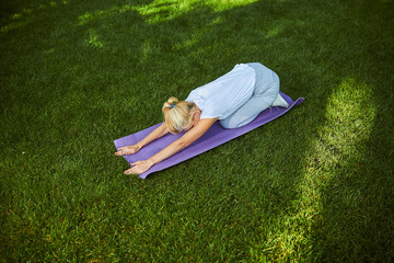 Blonde woman practicing yoga on sunny day in park