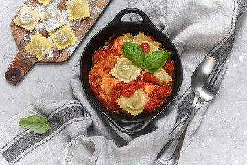 Ravioli tomato sauce with basil on black pan. top view, recipe  Italian cuisine.