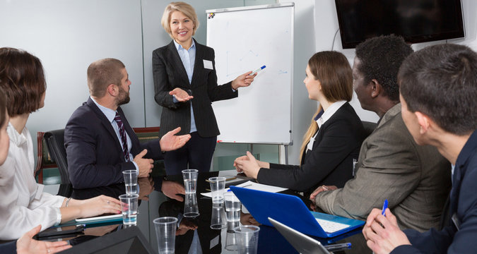 Successful adult business woman presenting new business strategy to partners in boardroom