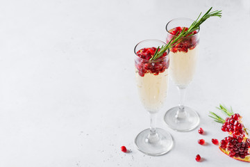 Pomegranate champagne rose with rosemary in tall glass on white background
