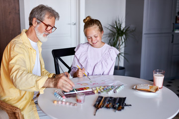senior grandfather teach little girl to draw, help to develop creativity, they use paints and brushes