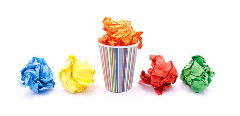 Colored wrinkled paper and paper cup, close up on white background