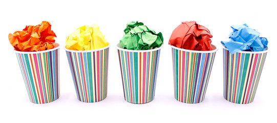 Colored wrinkled paper and paper cup, close up on white background
