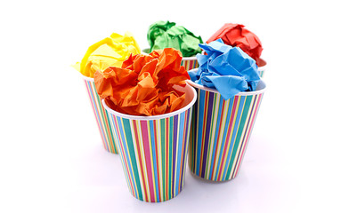 Colored wrinkled paper and paper cup, close up on white background
