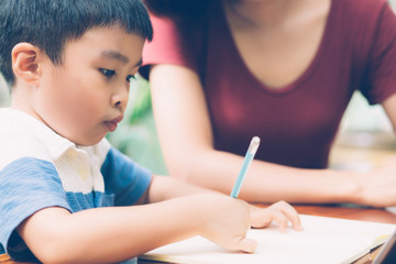 Son using digital tablet computer for study and learn to internet online with mother together, education from home, family recreation, mom teach boy and homework with technology, lifestyle concept.