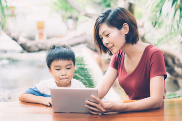 Son using digital tablet computer for study and learn to internet online with mother together, education from home, family recreation, mom teach boy with technology media, lifestyle concept.