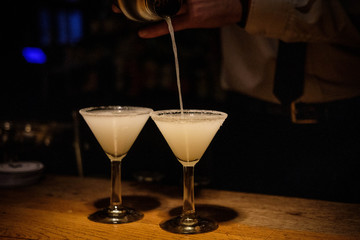 Night Club. Cocktails preparation. Margaritas in martini-glasses. Bartender hands making cocktails with a shaker. Elegant and classic.