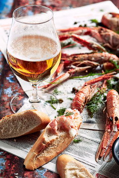 Prawns, bread and beer on newspaper