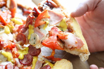 Male hand holding big piece of tasty fresh pizza