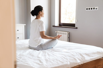Young asian woman practicing yoga at the bedroom