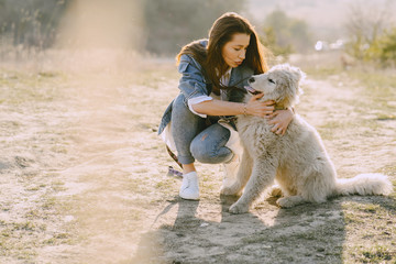 Woman in a spring forest. Girl with cute dog. Brunette in a jeans jacket.