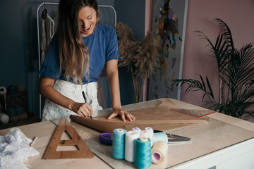 Young Caucasian smiling Woman measuring a pattern for cloth. Tailor concept. Sewing business concept. 