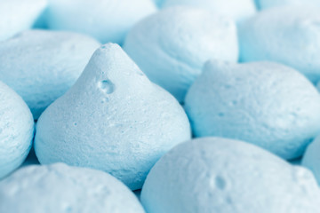 Fototapeta na wymiar Background of fresh sweet meringues of gentle blue color close-up. Fluffy candies cooked with eggs and sugar, homemade delicacy, creamy treat, dessert, baking decor, pastry shop, side view.