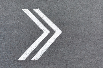 An arrow pointer is drawn with white paint on the road. Sign of turning to the right on the asphalt, direction of movement, path to follow. Background with copy space.