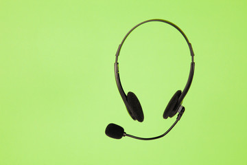 Online technical support service. Call center, helpline. Headphones with microphone on green...