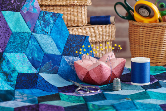Accessories for sewing, fragment of tumbling blocks quilt and baskets with tools for sewing and quilting on a brick wall background