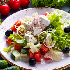 Fresh vegetables salad with feta cheese and black olives on a plate. Closeup. Macro view