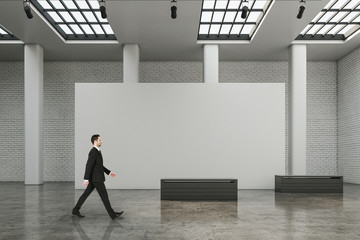 Businessman walking in contemporary exhibition hall interior