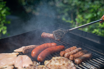 Garden barbecue - grilling steak, sausages, kebabs and chicken meat - close-up