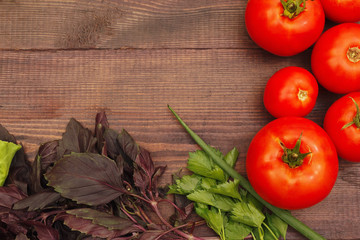 Tomatoes, basil and parsley on a wooden table. View from above.