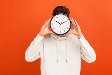 Don't waist your time! Man in casual white sweatshirt holding wall clock hiding his face, time...