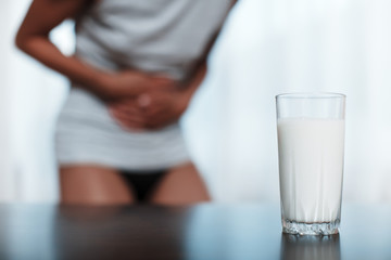 lactose intolerance concept. A woman feels bad, has an upset stomach, bloating due to lactose...