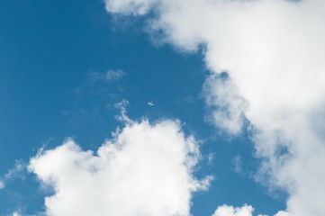 The aircraft in the air. Clear blue sky with clouds from which a passenger airliner takes off. The plane in the air carries passengers on vacation at sea. Traveling by plane.