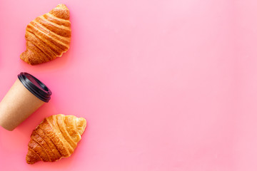 Coffee and croissants on pink background top view