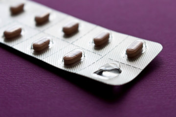 Package of pills on a purple background. Close up. Selective focus.