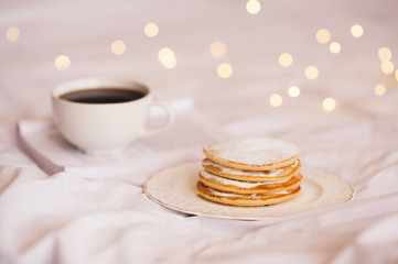 Pancakes with cream cheese with cup of coffee over glowing lights closeup. Breakfast time. Good morning. Selective focus.