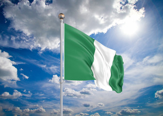 Realistic flag. 3D illustration. Colored waving flag of Nigeria on sunny blue sky background.