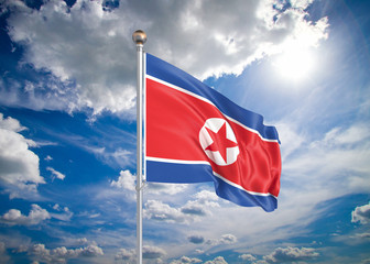 Realistic flag. 3D illustration. Colored waving flag of North Korea on sunny blue sky background.