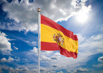 Realistic flag. 3D illustration. Colored waving flag of Spain on sunny blue sky background.